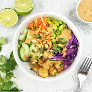 quinoa salad in bowl from above with peanut sauce and limes