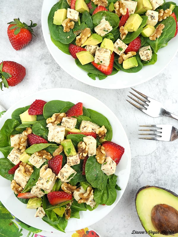 easy vegan spinach salad with strawberries, avocado, walnuts, and dairy-free feta in two bowls from above