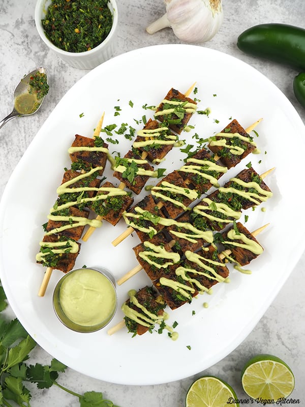 Seitan Skewers on platter with chimichurri, limes, garlic, and peppers