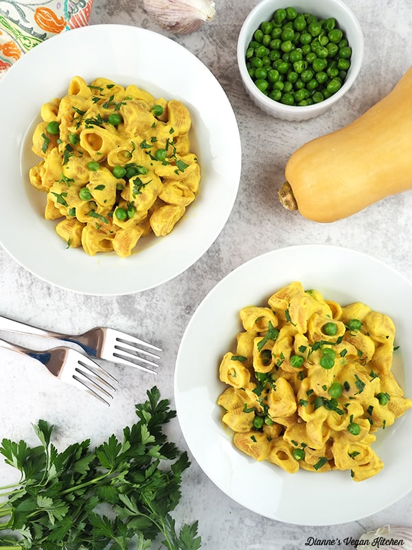 two bowls oVegan Butternut Squash Mac and Cheese with forks, peas, and squash