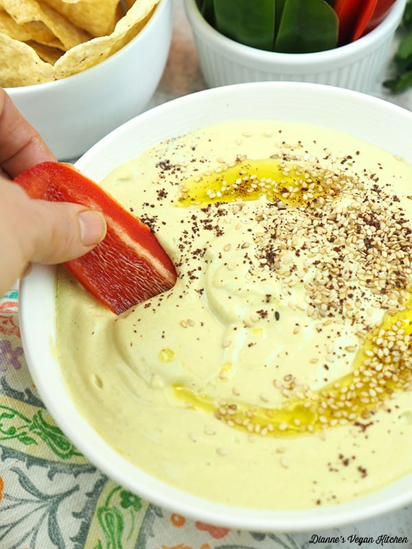 dipping a piece of pepper into hummus