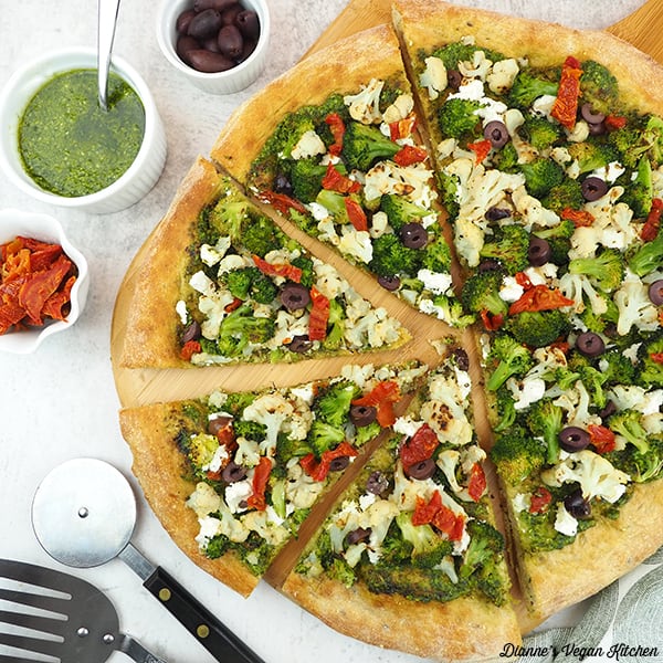 pizza with olives, pesto, sun-dried tomatoes, and pizza cutter