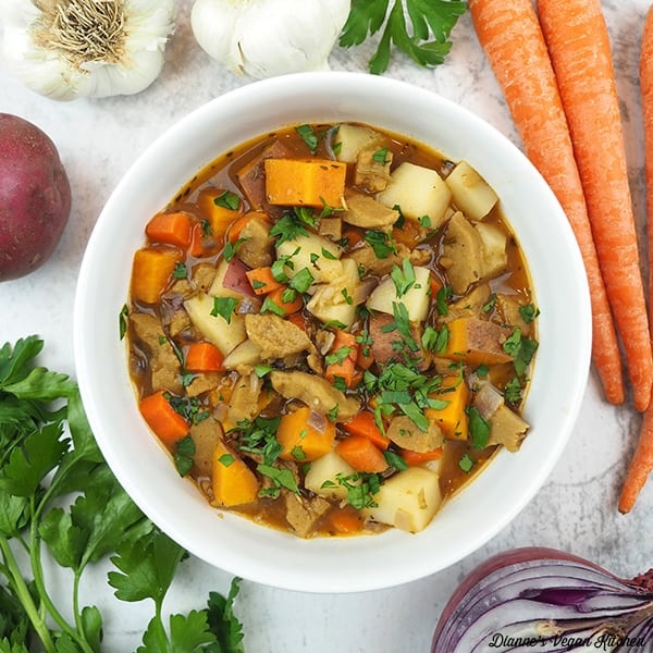 of Seitan Stew overhead with carrots, onion, garlic, potatoes, and parsley, square