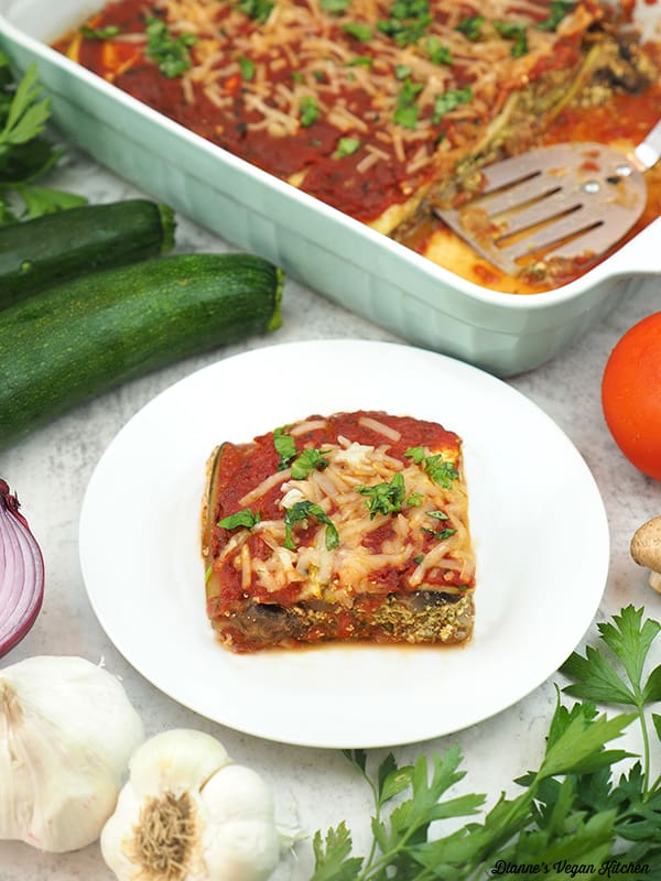 slice of lasagna with pan, zucchini, onion, garlic, tomatoes