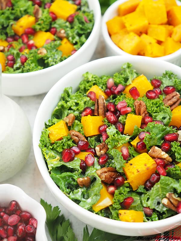 holiday kale salad with dressing, squash, and pomegranate seeds