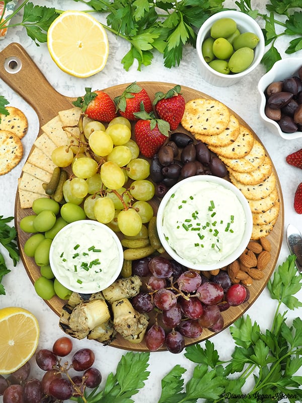cheese board with crackers, olives, grapes, artichoke hearts, strawberries, almonds