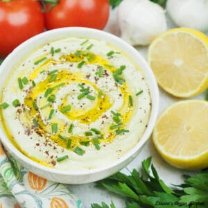 bowl of hummus with lemons, garlic, and tomatoes