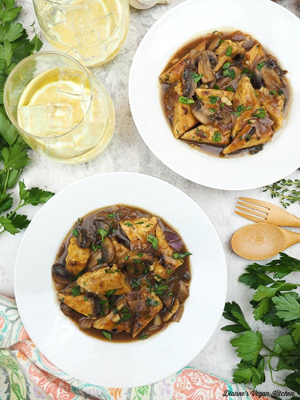 two bowls of Tempeh Bourguignon with lemon water