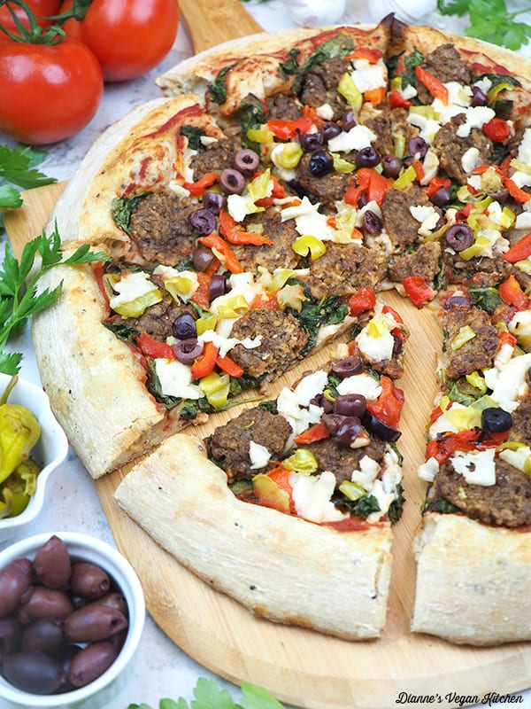pizza slices on paddle with tomatoes, garlic, olives, and peppers
