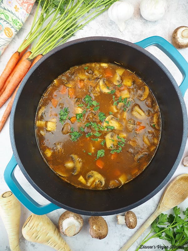 pot of stew with carrots, parsnips, garlic, and mushrooms with spoon