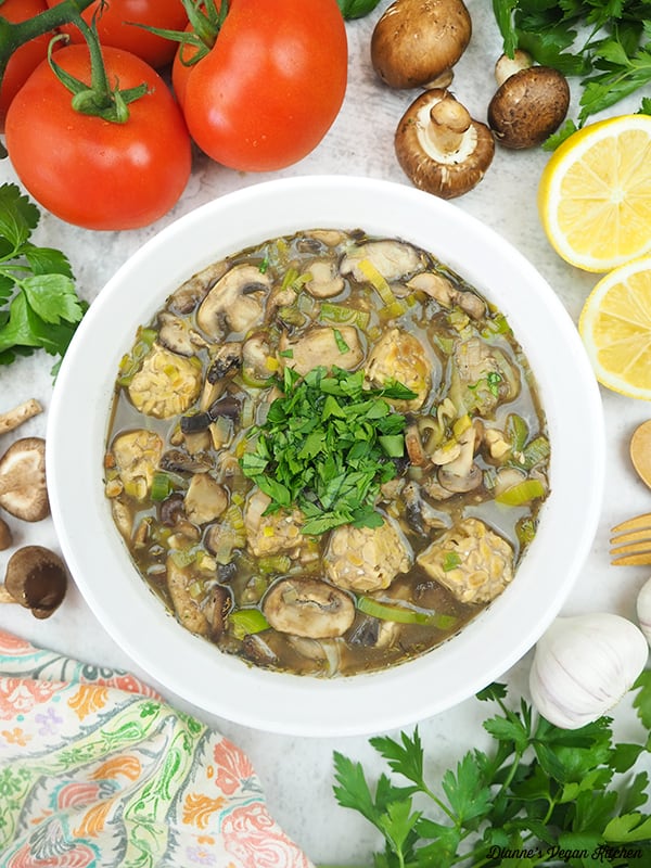 serving bowl of fricassee with mushrooms, tomatoes, and lemon
