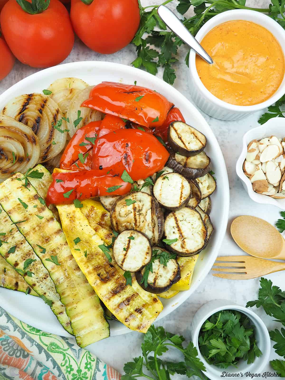 plate of grilled vegetables with tomatoes, eggplant, romesco, and almonds