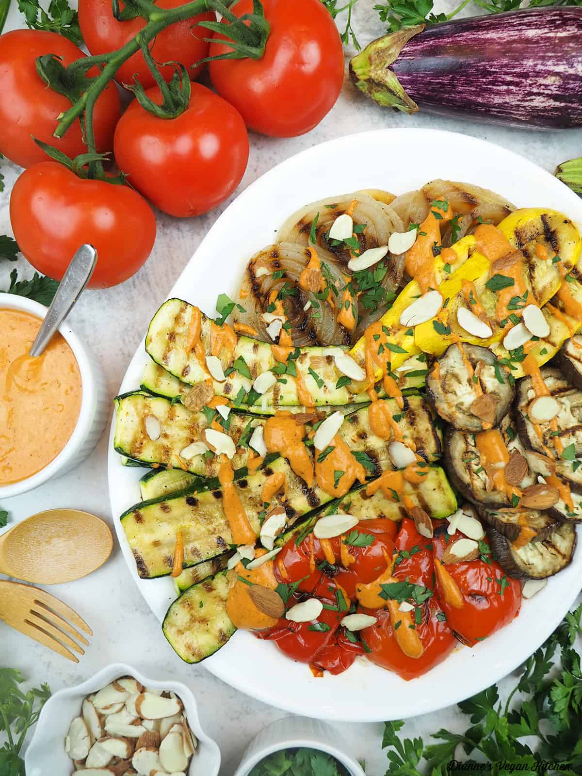 platter of grilled vegetables with tomatoes, eggplant, romesco, and almonds
