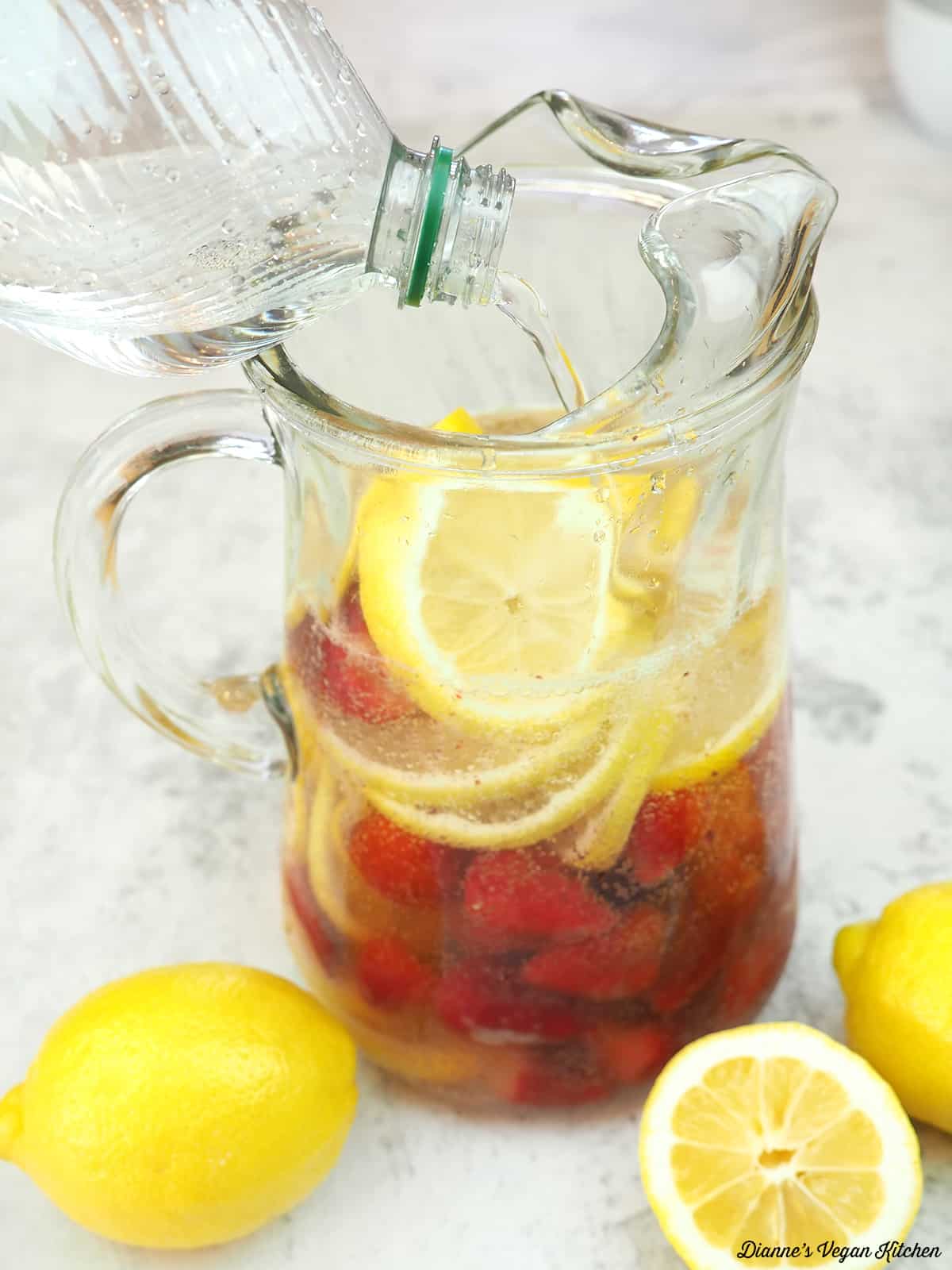 pouring water in pitcher of sangria