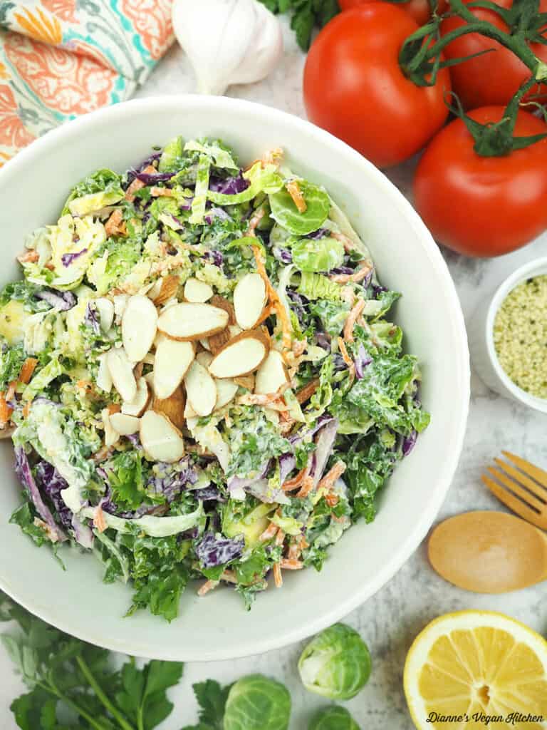 Cruciferous Crunch Salad with almonds, tomatoes, brussels sprouts, lemon, fork and spoon