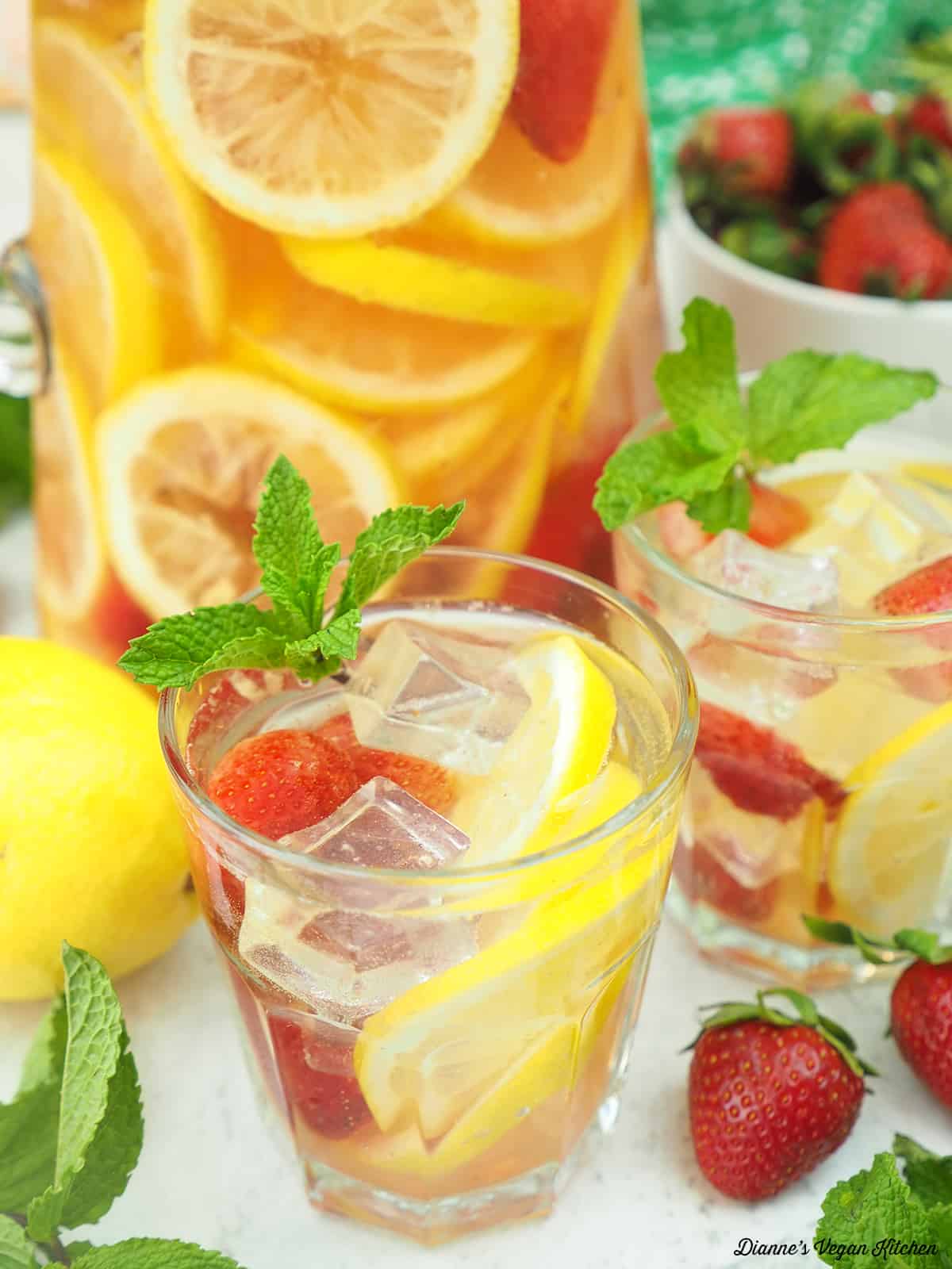 two glasses of white wine sangria with lemons and strawberries