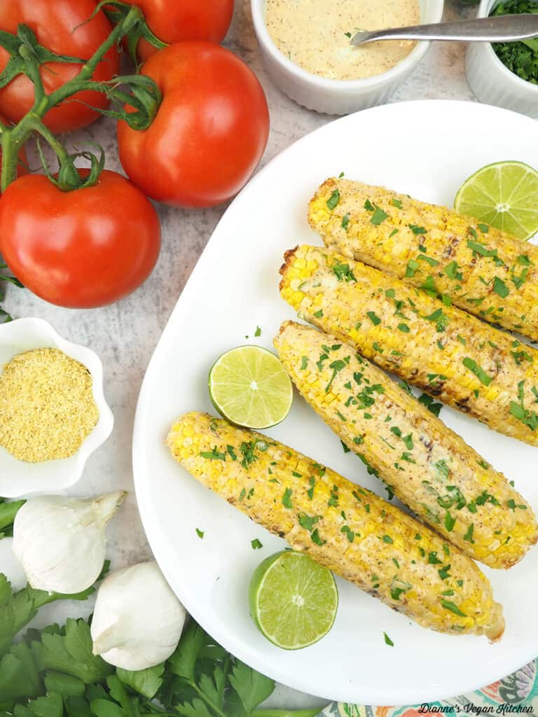 platter with corn, tomatoes, parsley, sauce, parmesan,and limes