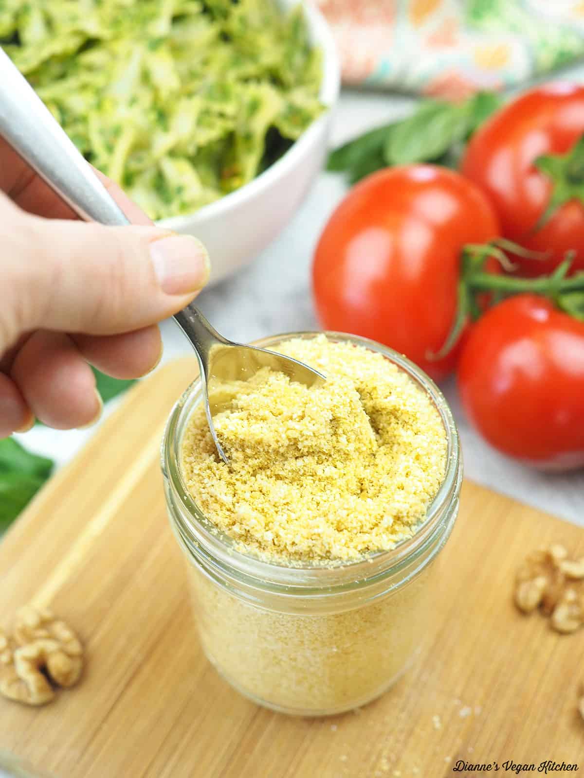 dipping a spoon into jar of parmesan