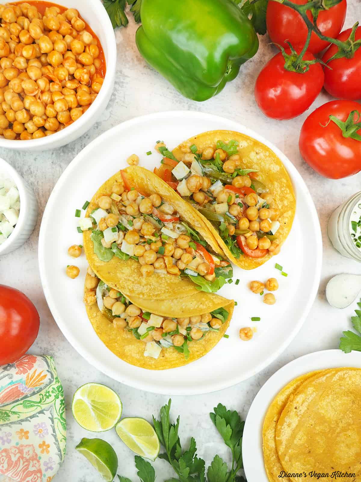 plate of tacos with tomatoes, peppers, buffalo chickpeas, cucumber ranch, lemons, and tortillas,
