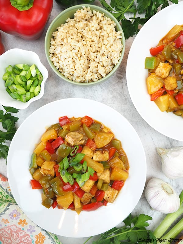 two bowls of sweet and sour tofu with peppers, rice, garlic, and scallions
