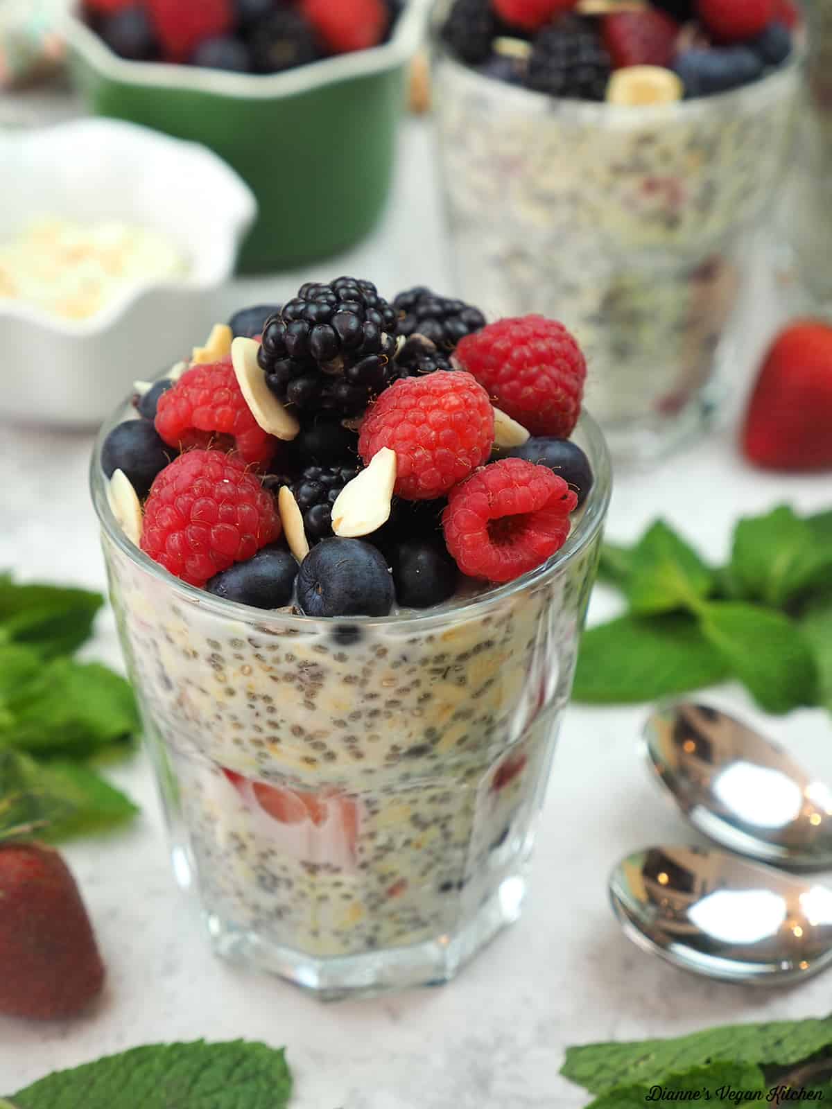 overnight oats with berries, spoons, and mint leaves