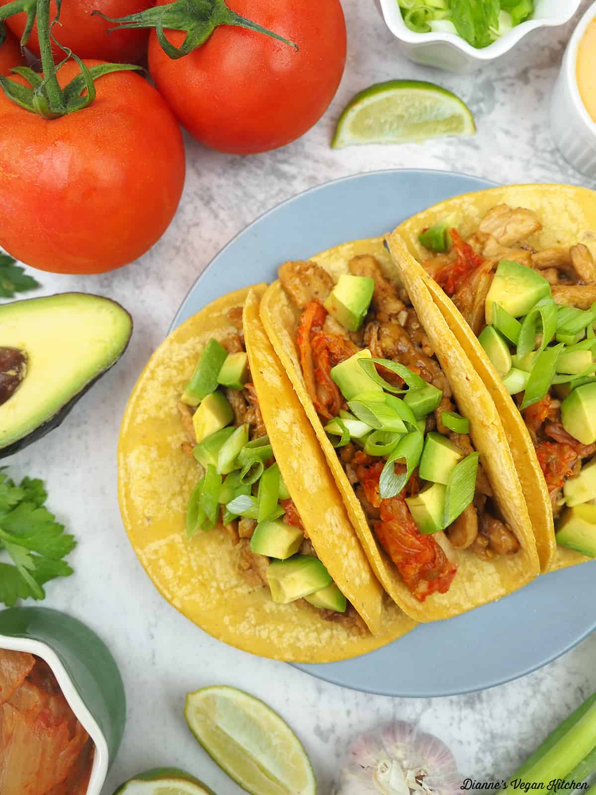 tacos with tomatoes, avocado, limes, scallion, spicy mayo, kimchi, avocado, and garlic