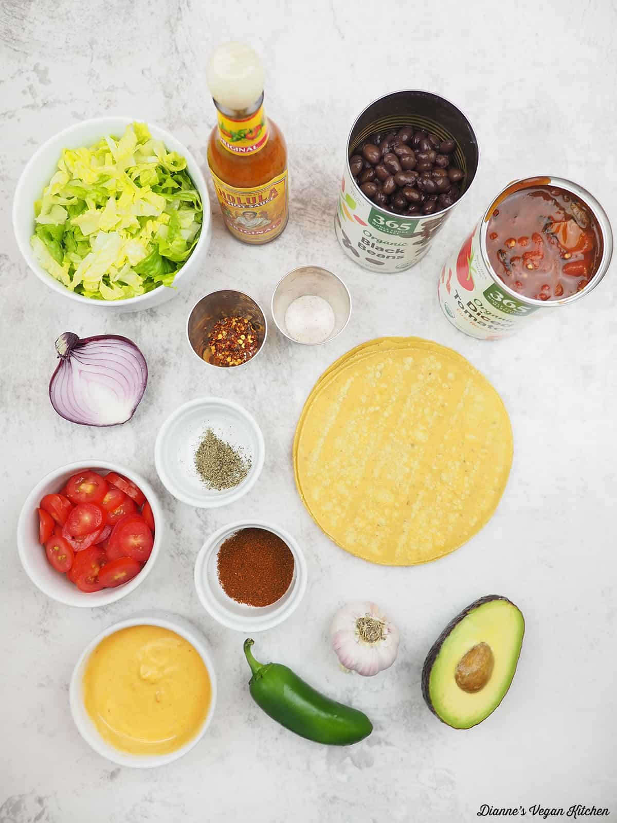 lettuce, hot sauce, black beans, diced tomatoes, tostadas, avocado, onion, jalapeno, garlic, cheese sauce, spices, tomatoes, onion