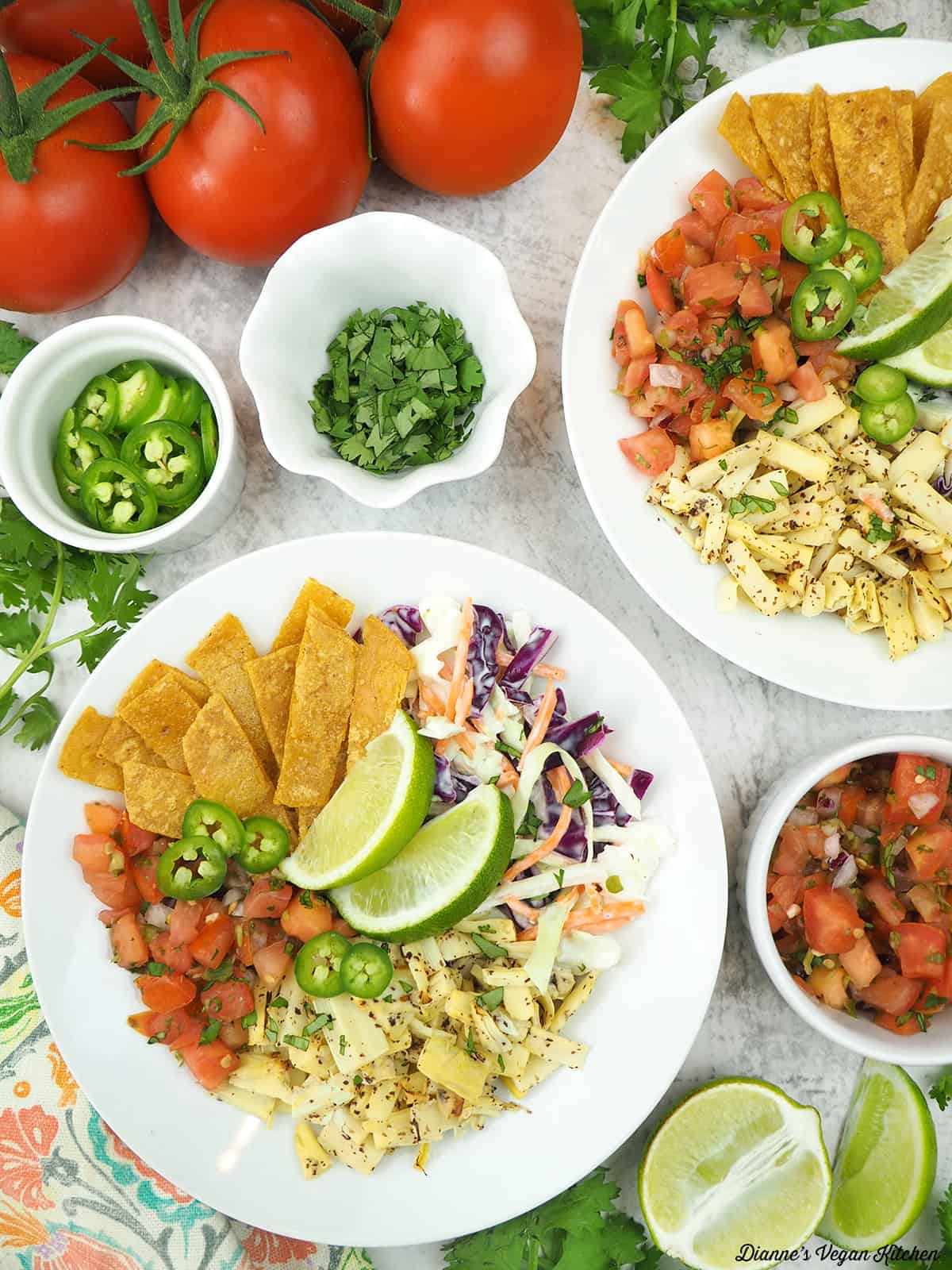 two vegan fish taco bowls with limes, salsa, cilantro, jalapeños, and tomatoes