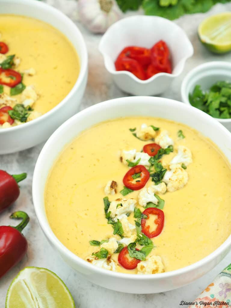 two bowls of Curried Cauliflower Soup with peppers, lime, and basil