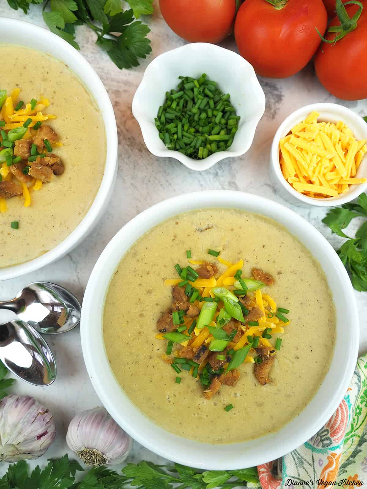 two bowls of soup with scallions, chives, tempeh bacon, and vegan cheddar