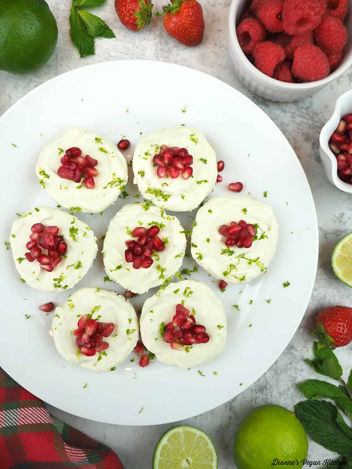 plate of cheesecakes with berries, limes, and mint leaves