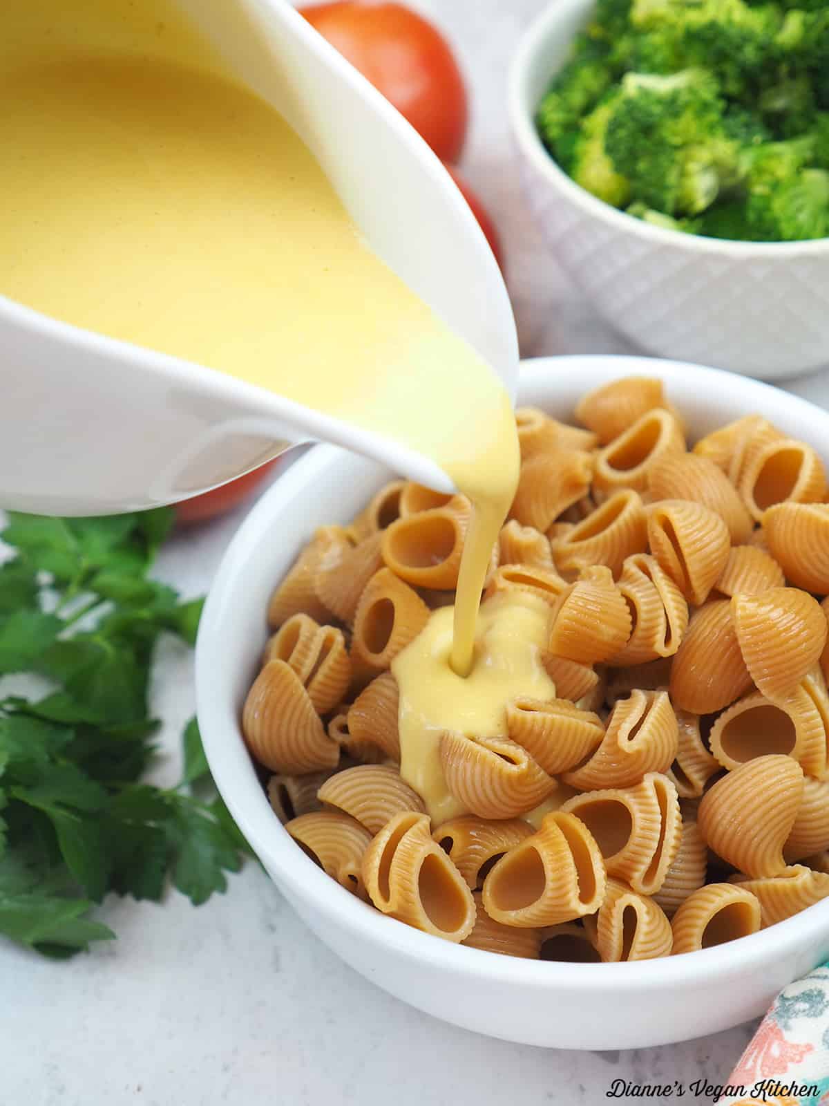 pouring cheese sauce over pasta