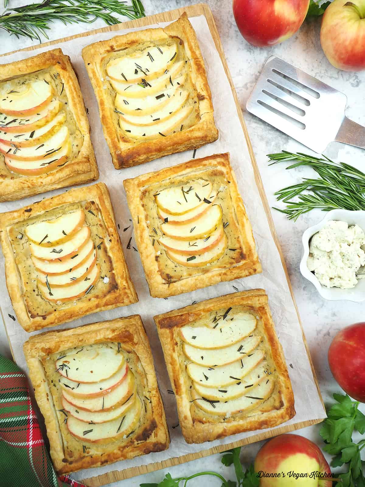Vegan Apple and Cheese Tarts with apples, cheese, rosemary, and a spatula