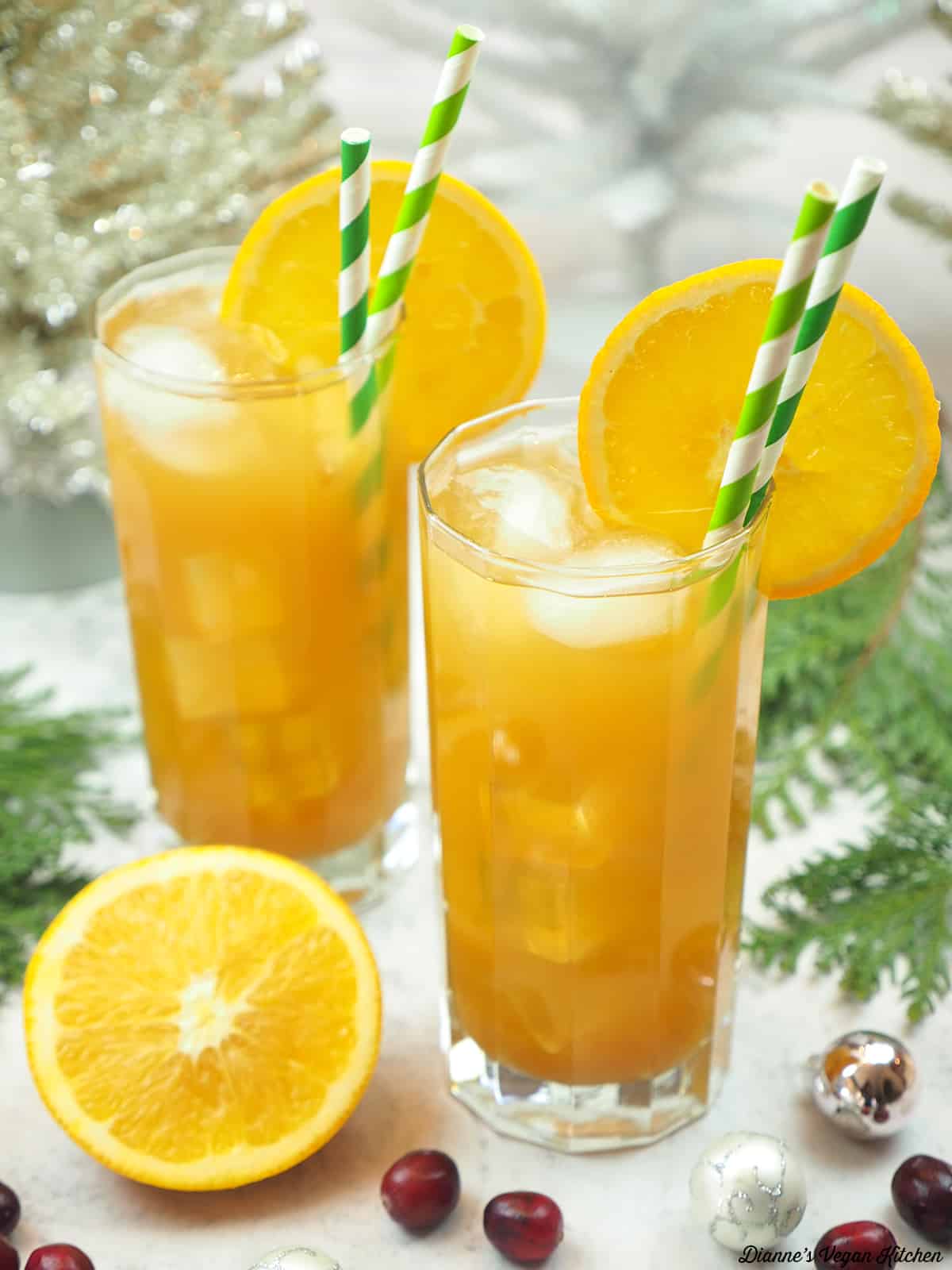 two glasses of sparkling iced with with an orange and cranberries