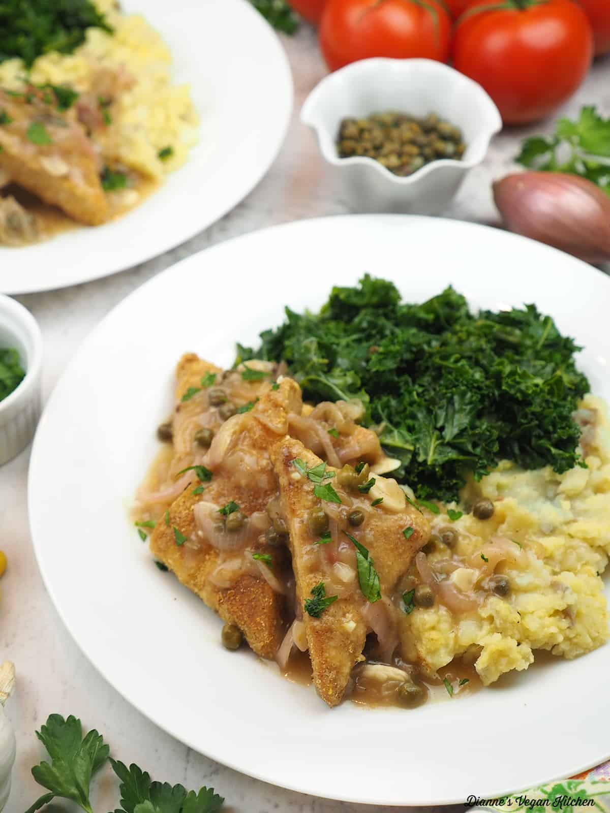 plate of tempeh piccata with mashed potatoes and sautéed kale