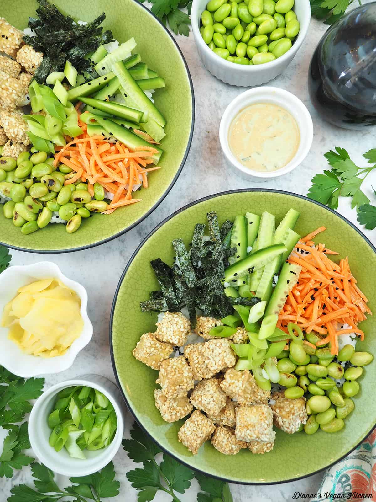 two sushi bowls with edamame, soy sauce, scallions, ginger, and miso carrot dressing