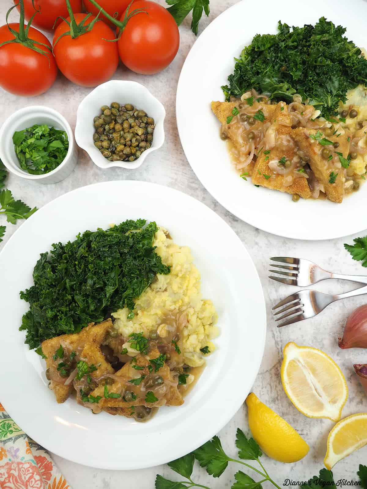two plates of tempeh piccata with cappers, lemons, shallots, tomatoes, parsley, and lemon