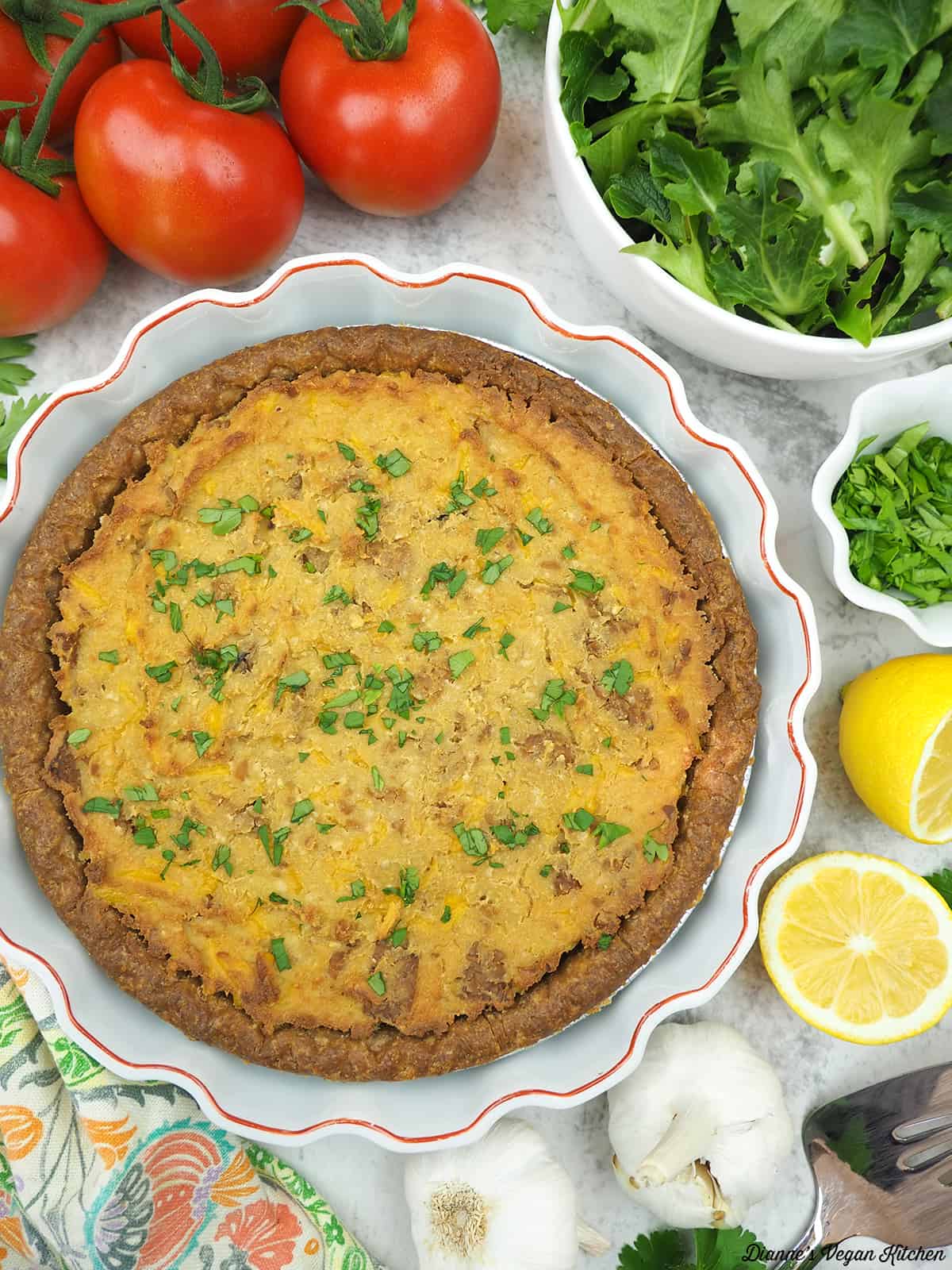 Vegan Quiche Lorraine with tomatoes, salad, lemons, garlic, and parsley