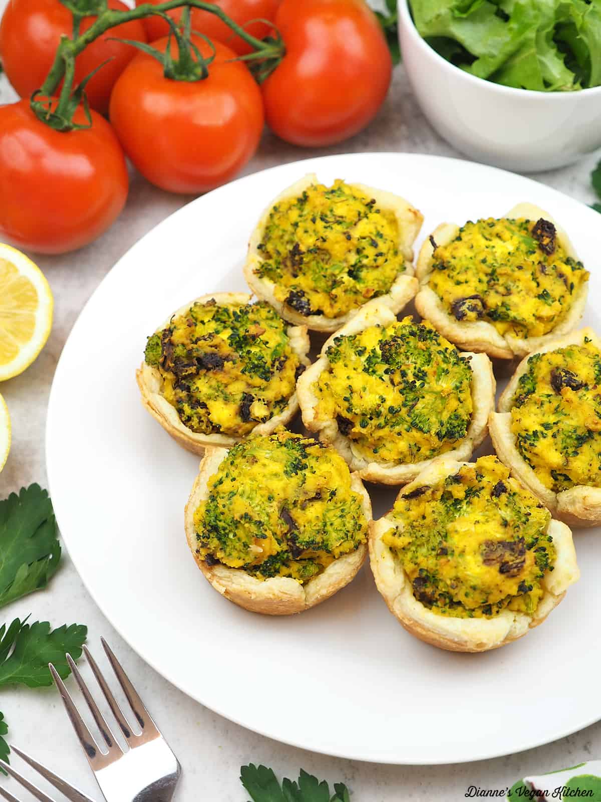 plate of Vegan Broccoli Quiche Cups with tomatoes, a salad, and forks