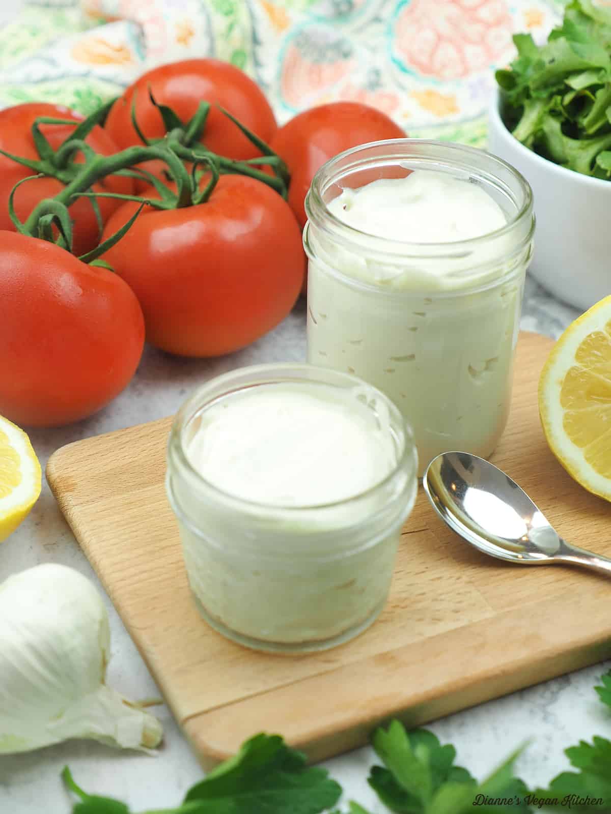Two jars of vegan mayonnaise with tomatoes, lettuce, lemon and garlic