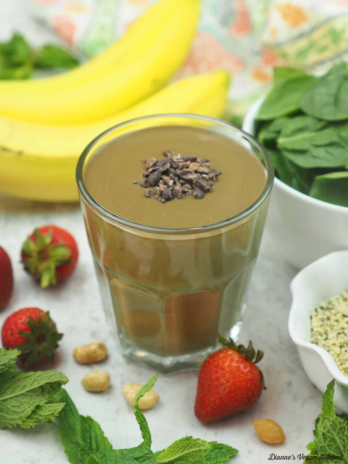 A smoothie with bananas, spinach, strawberries, mint leaves, peanuts and flax seeds