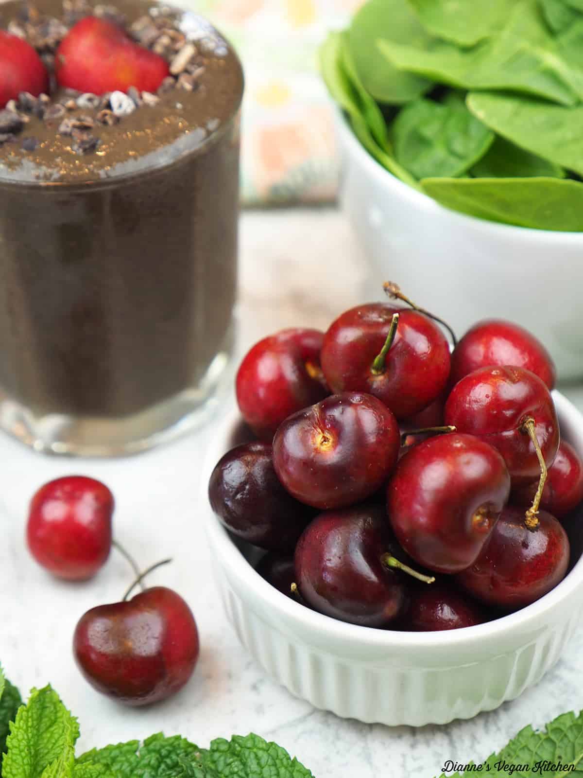 bowl of cherries with a smoothie in the background