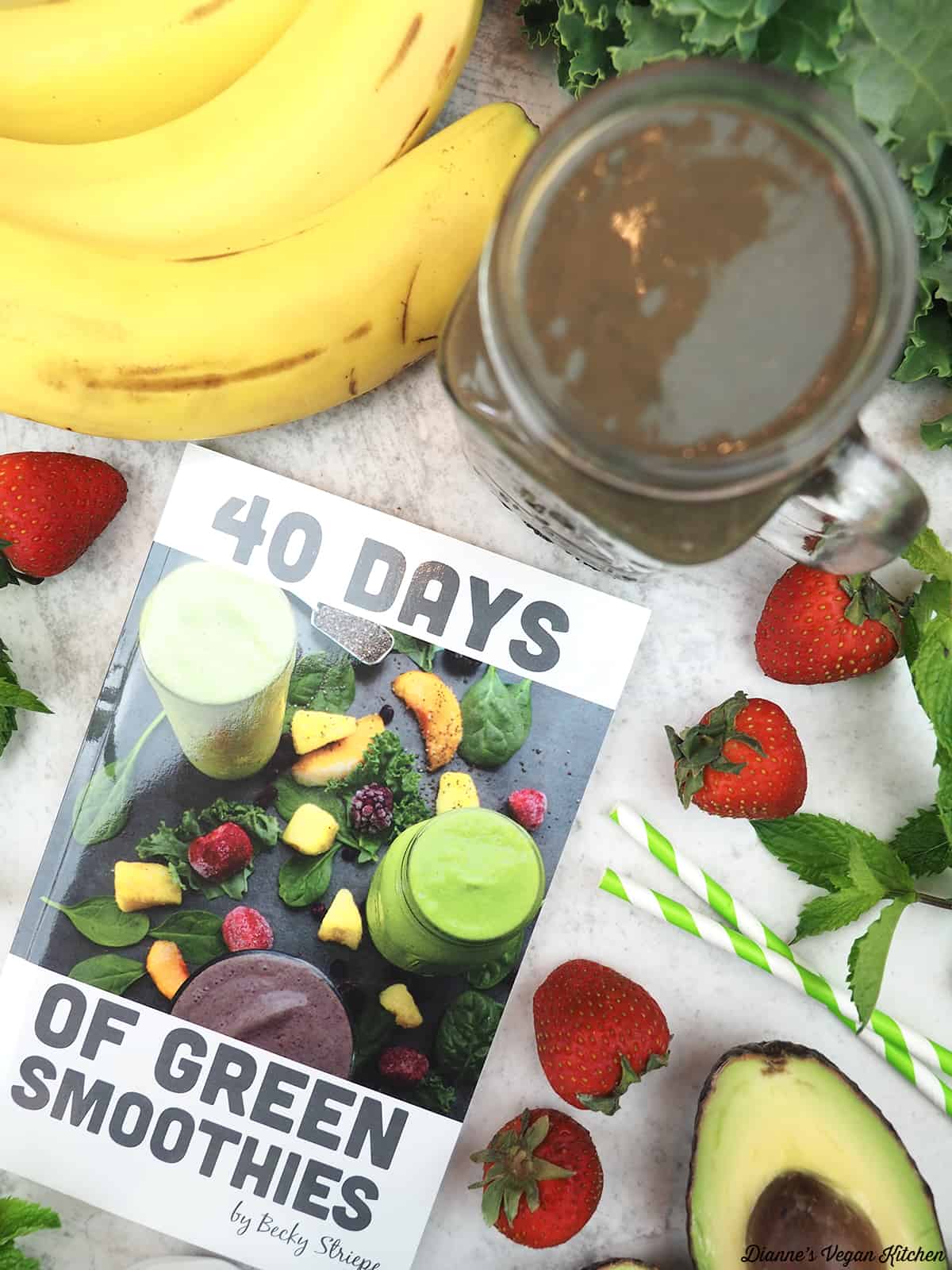40 Days of Green Smoothies book with a chocolate shake, bananas, strawberries, and an avocado