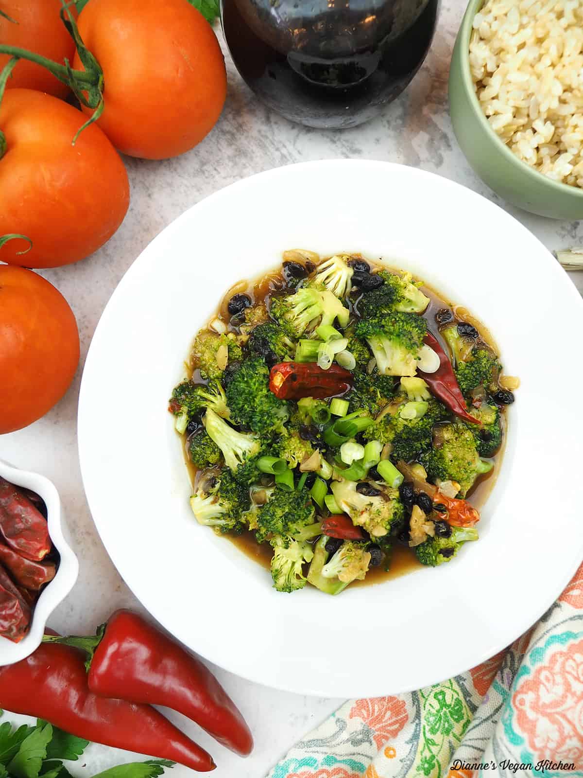 one bowl of Broccoli with Black Bean Sauce with red chilis, brown rice, tomatoes, and soy sauce