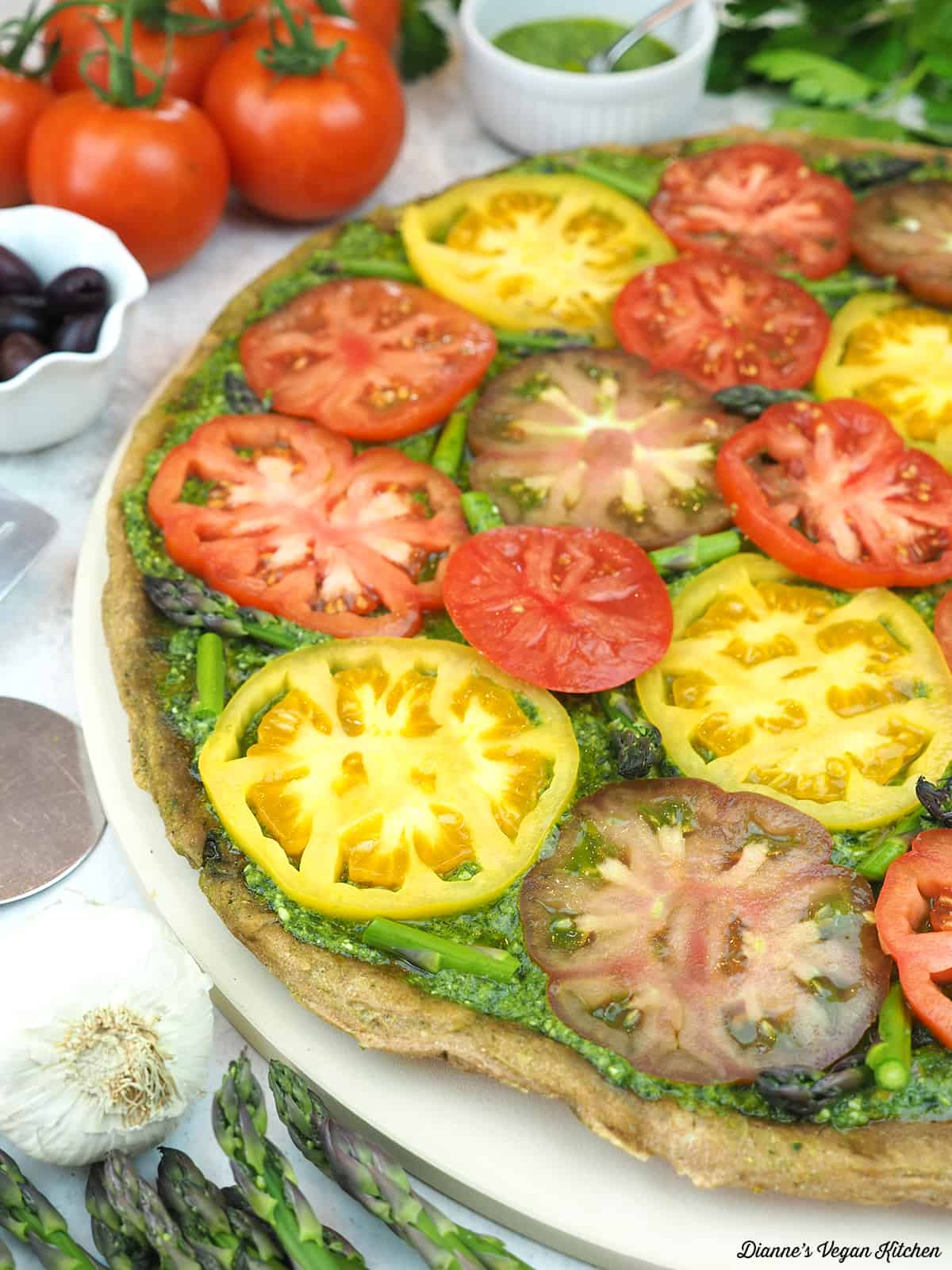 Grilled Pesto Tart with Tomatoes with tomatoes, pesto, olives, garlic, and asparagus