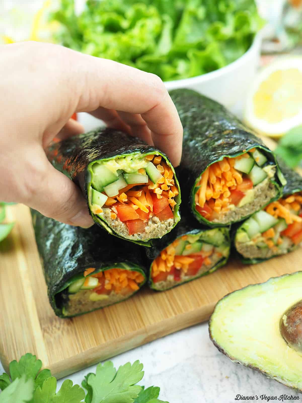 a hand taking a sushi wrap from a stack