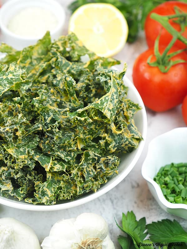 kale chips in bowl with tomatoes, garlic, lemon, and chives